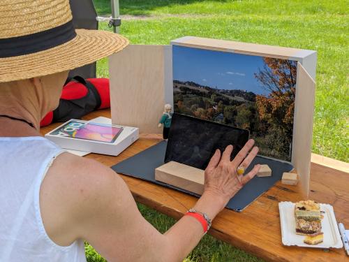 Frau mit Tablet vor offener Kiste mit Holzfiguren